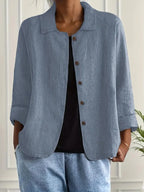 Woman wearing a blue collared button-front long sleeve blazer in a studio setting