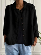 Woman wearing a black collared button-front long sleeve blazer in a studio setting