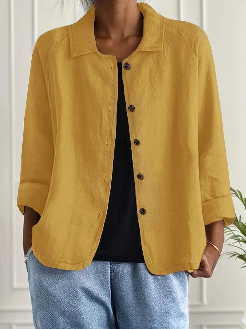 Woman wearing a yellow collared button-front long sleeve blazer in a studio setting
