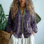 Woman wearing a purple embroidered floral print v-neck long sleeve blouse in a studio setting