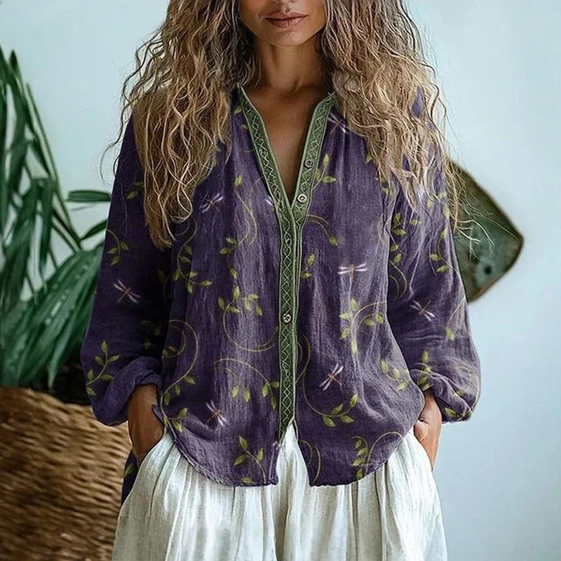 Woman wearing a purple embroidered floral print v-neck long sleeve blouse in a studio setting