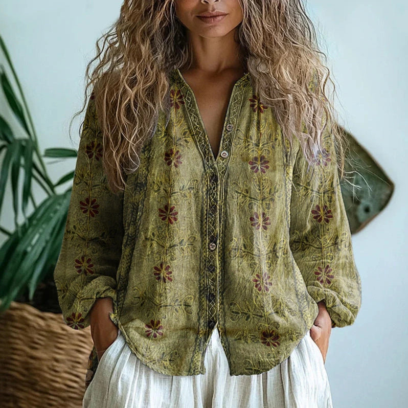 Woman wearing a green embroidered floral print v-neck long sleeve blouse in a studio setting