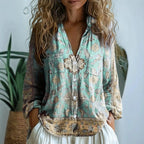 Woman wearing a turquoise embroidered floral print v-neck long sleeve blouse in a studio setting