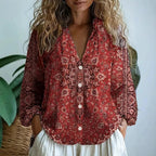 Woman wearing a red embroidered floral print v-neck long sleeve blouse in a studio setting