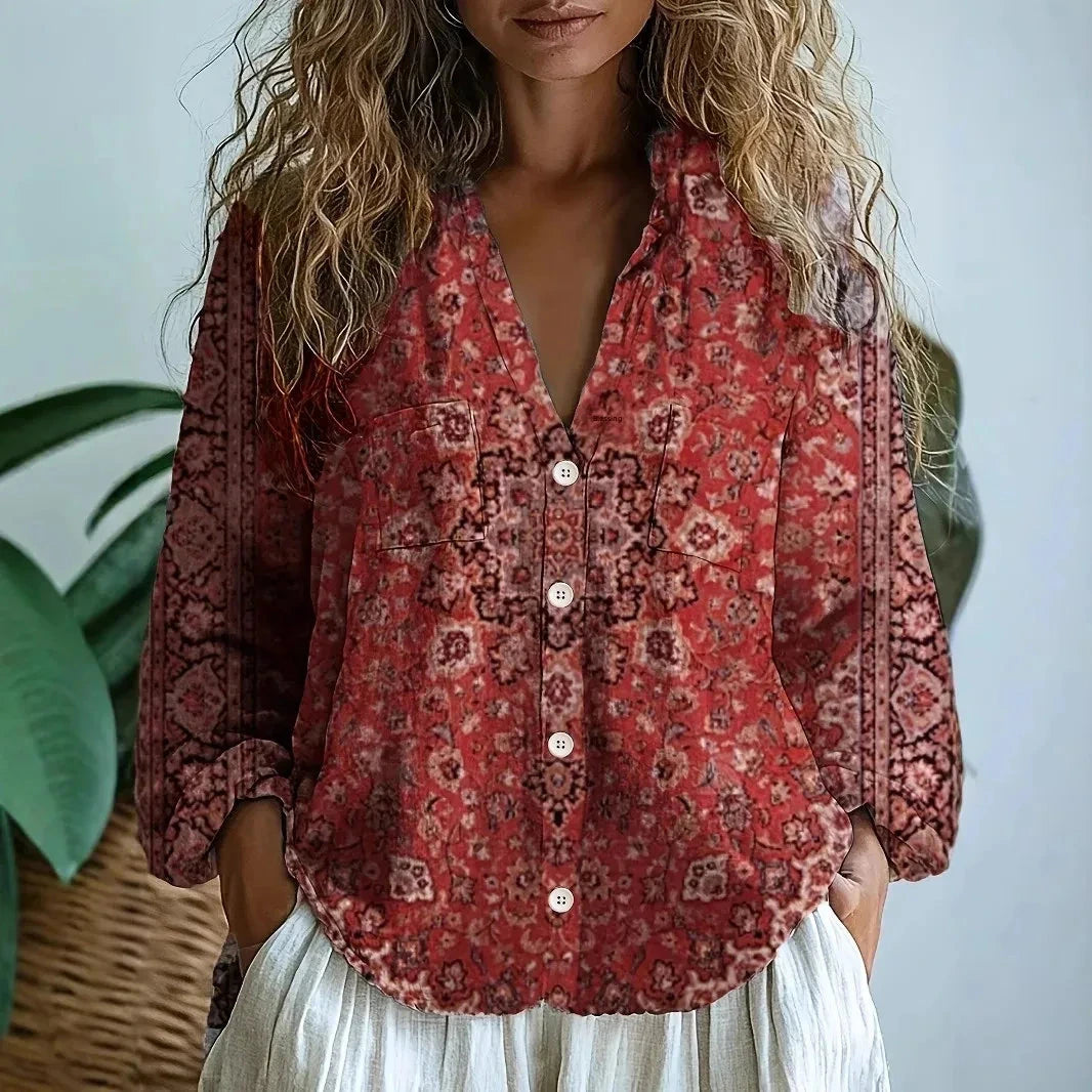 Woman wearing a red embroidered floral print v-neck long sleeve blouse in a studio setting
