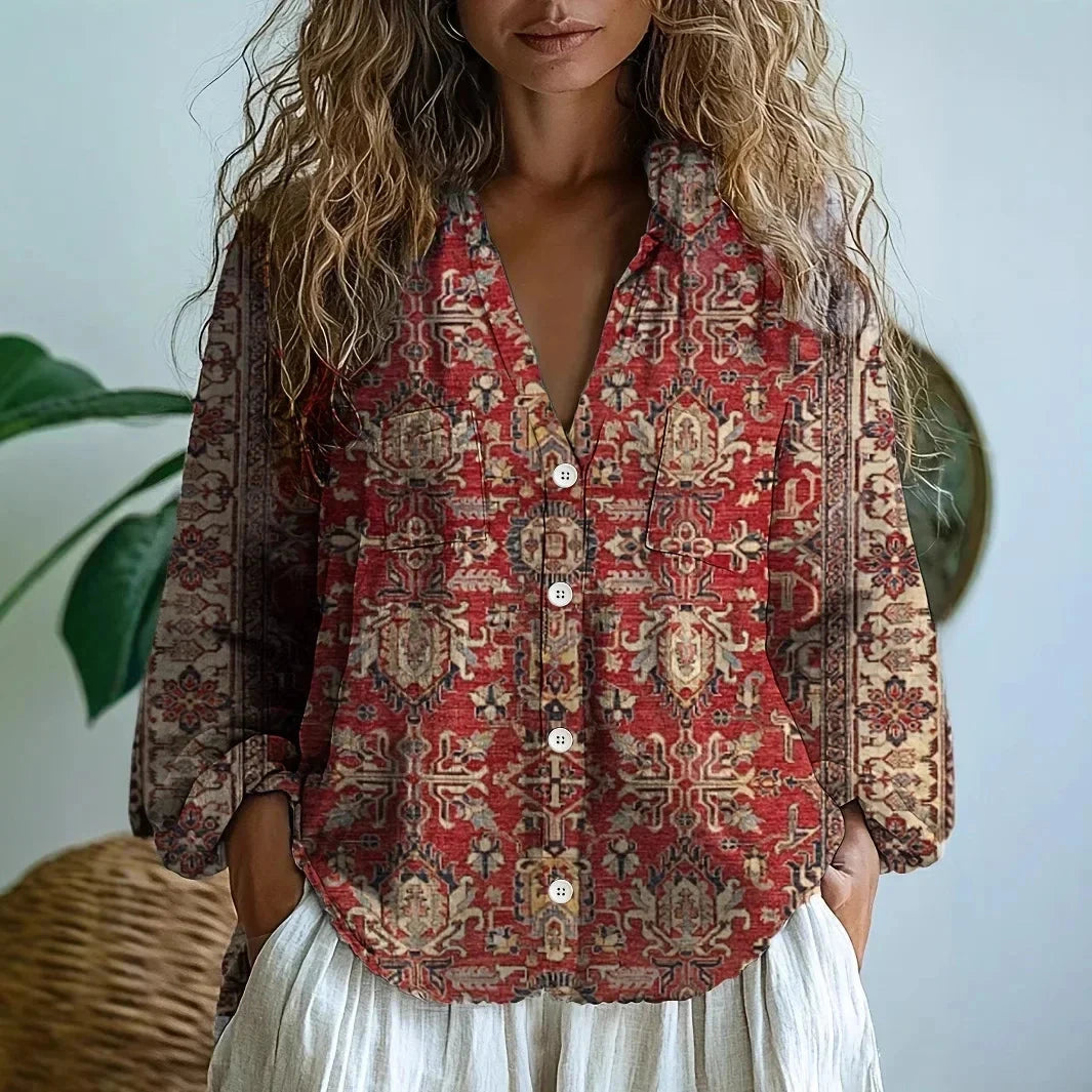 Woman wearing a burgundy embroidered patchwork print v-neck long sleeve blouse in a studio setting