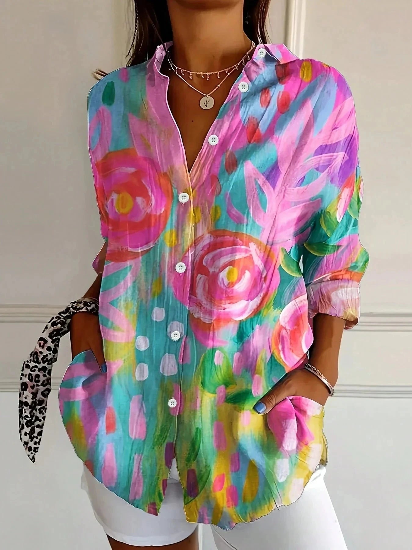 Woman wearing a pink abstract floral print button-down blouse in a studio setting