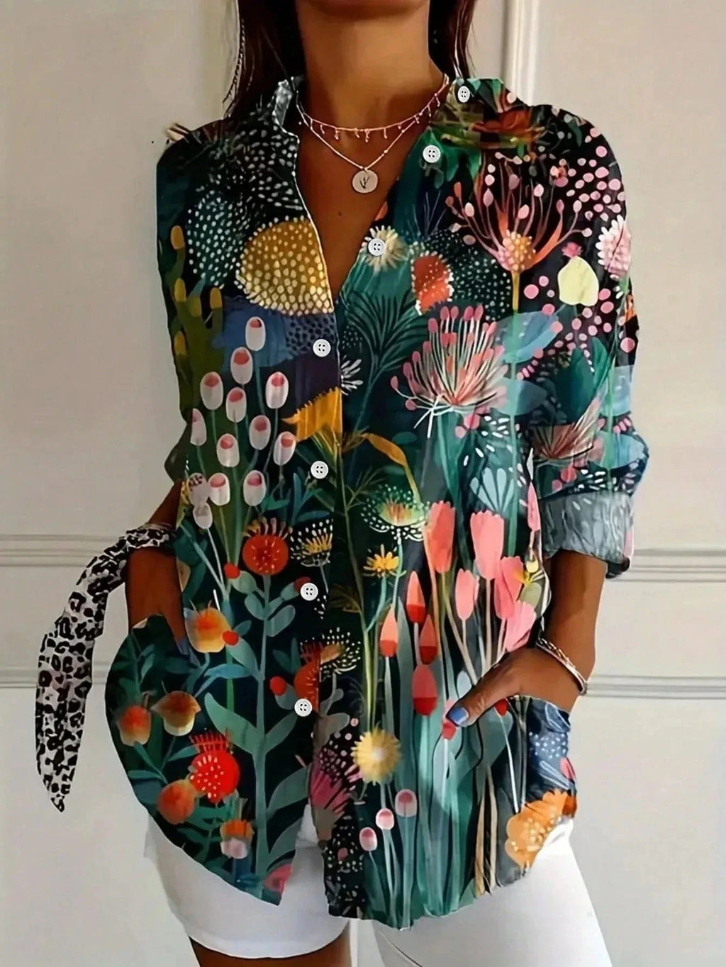 Woman wearing a green botanical print button-down blouse in an outdoor setting