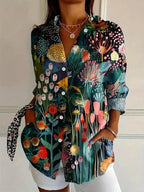 Woman wearing a green botanical print button-down blouse in an outdoor setting