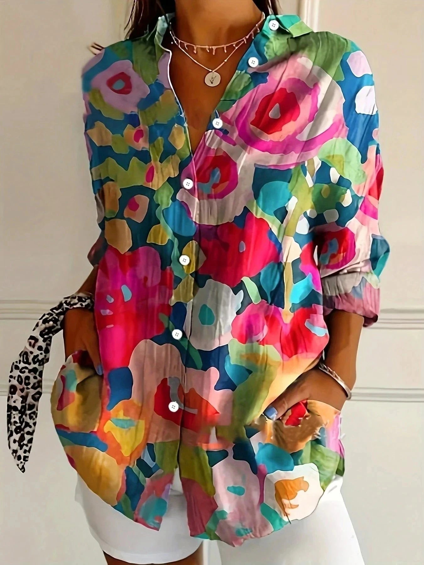 Woman wearing a mix colorful abstract floral print button-down blouse, back view in a studio setting