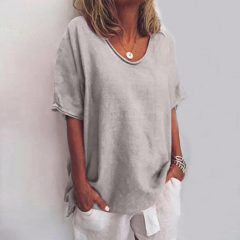 Woman wearing a light grey v-neck short sleeve loose blouse in a studio setting