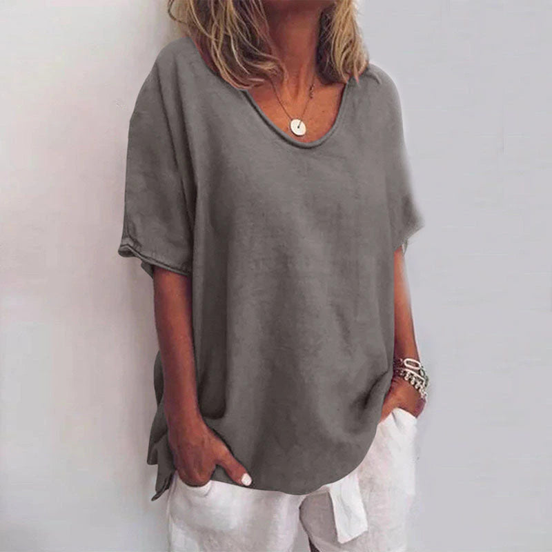 Woman wearing a grey v-neck short sleeve loose blouse in a studio setting