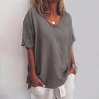 Woman wearing a grey v-neck short sleeve loose blouse in a studio setting
