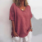 Woman wearing a dark pink v-neck short sleeve loose blouse, alternate shade in a studio setting