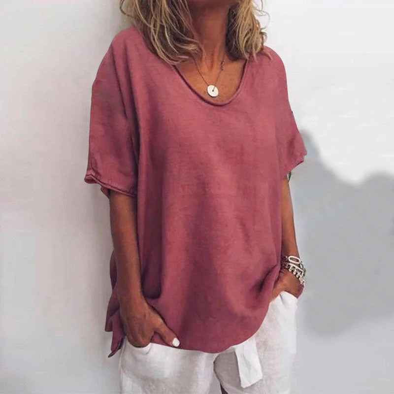 Woman wearing a dark pink v-neck short sleeve loose blouse, alternate shade in a studio setting