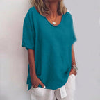 Woman wearing a teal v-neck short sleeve loose blouse in a studio setting
