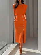 Woman wearing an orange button front sleeveless midi dress in a studio setting