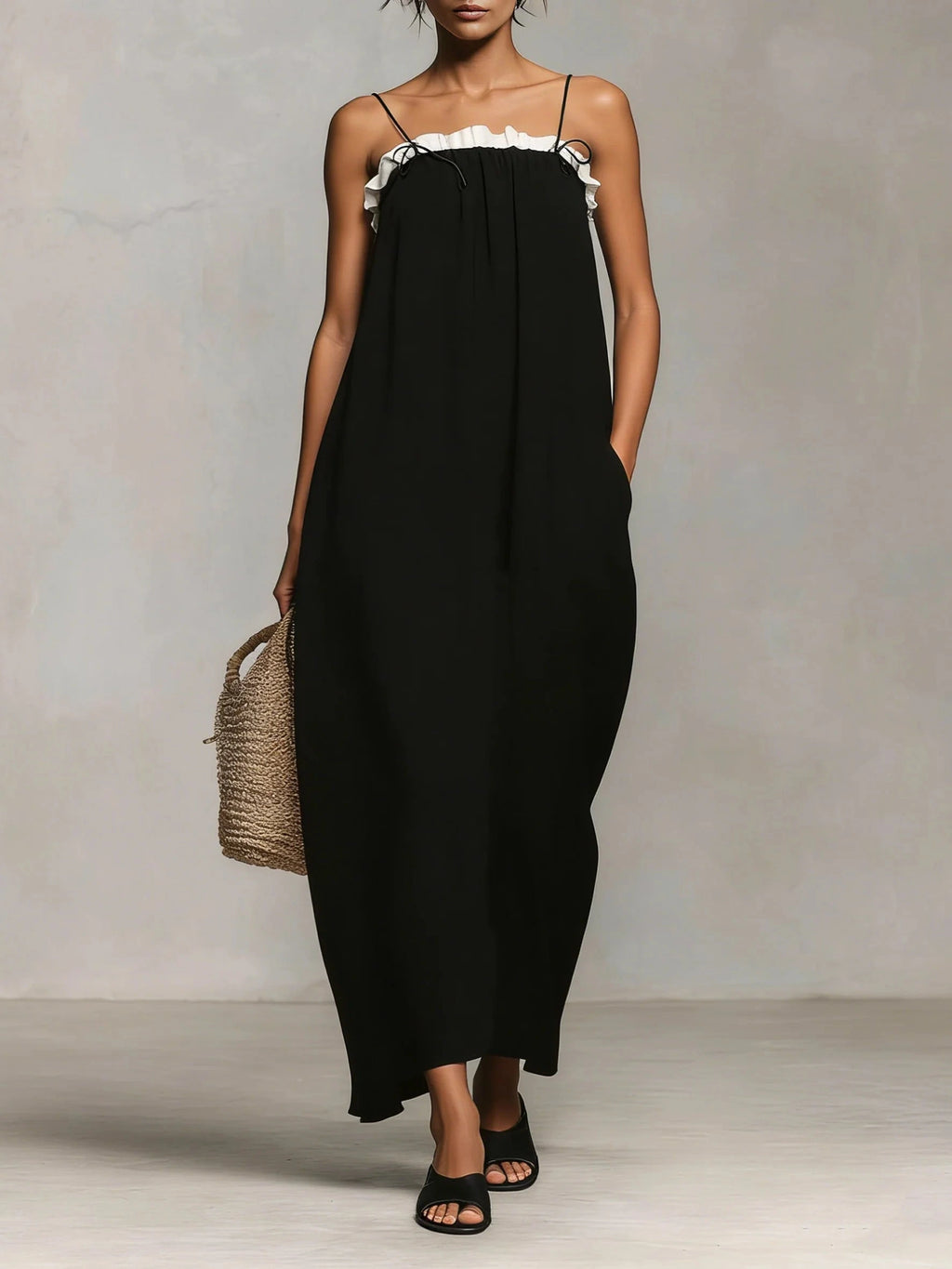 Woman wearing a black spaghetti strap maxi dress with a white ruffle trim, front view