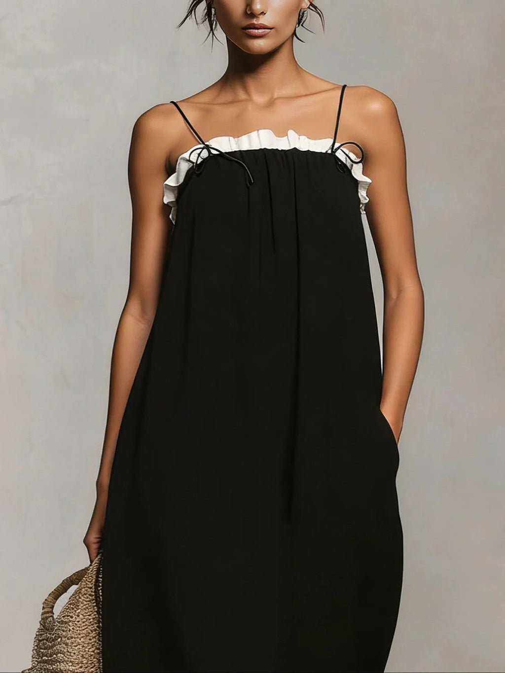 Woman wearing a black spaghetti strap maxi dress with a white ruffle trim, close-up front view