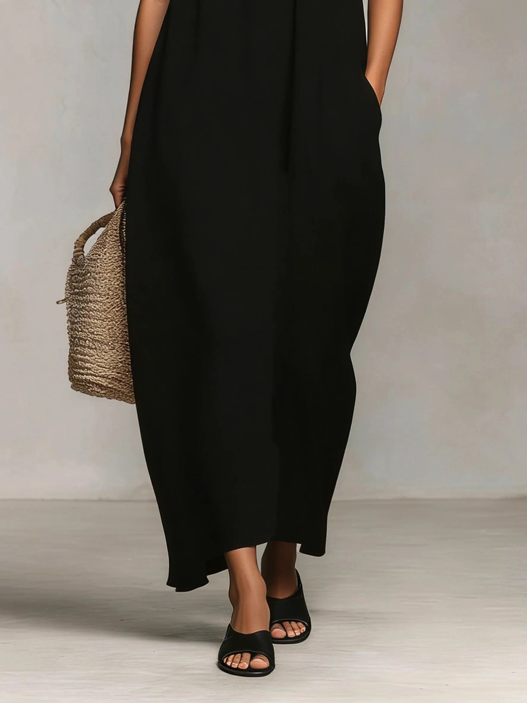 Close-up of a black spaghetti strap maxi dress showing the skirt and pockets