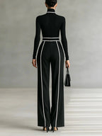 Woman wearing a black turtleneck and black wide-leg trousers with white contrast piping, back view
