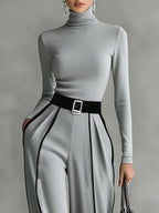 Close-up of gray wide-leg trousers with white contrast piping and belt detail