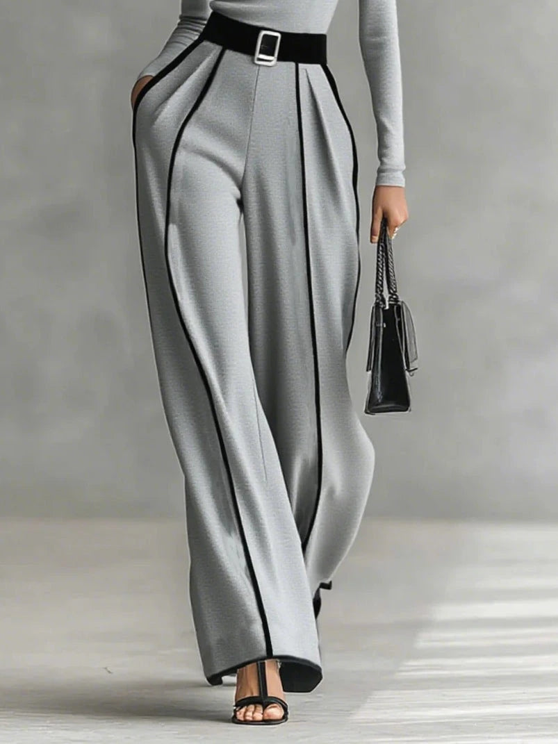 Woman wearing a gray turtleneck and gray wide-leg trousers with white contrast piping, full-length view