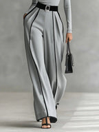 Woman wearing a gray turtleneck and gray wide-leg trousers with white contrast piping, full-length view