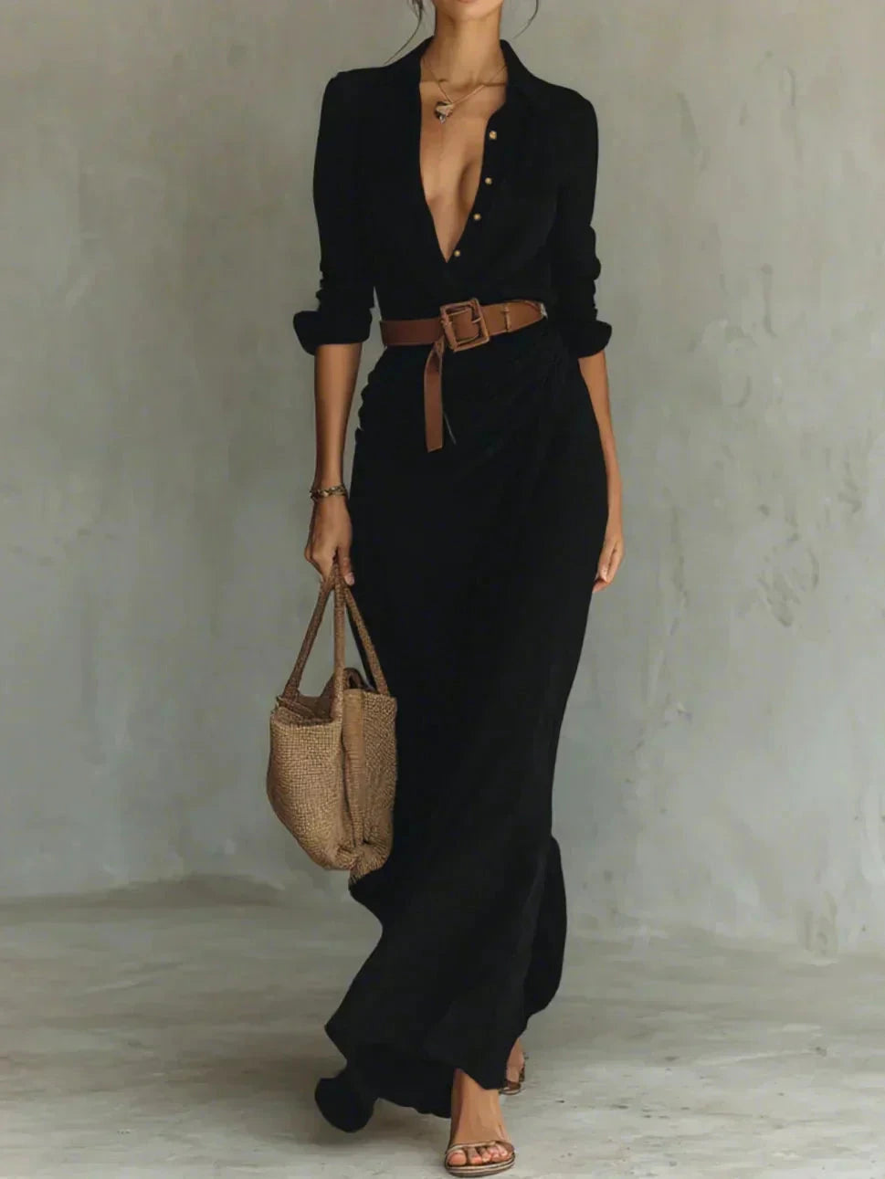 Woman wearing a black lapel collar wrap maxi dress with a brown belt, studio setting