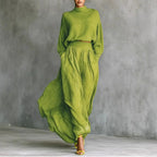 Woman wearing a yellow-green lightweight flowing midi dress with a turtleneck top, front view