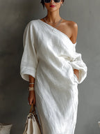 Woman wearing a white one-shoulder draped maxi dress, close-up front view