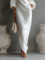 Woman wearing a white one-shoulder draped maxi dress, close-up of the skirt