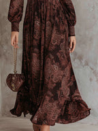 Woman wearing a brown paisley print long-sleeve fitted maxi dress, close-up of the skirt