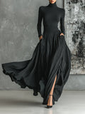 Woman wearing a black pleated maxi skirt with a black turtleneck top, studio setting