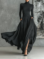 Woman wearing a black pleated maxi skirt with a black turtleneck top, studio setting