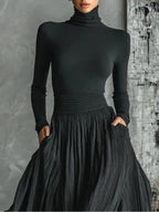 Woman wearing a black pleated maxi skirt with a black turtleneck top, close-up front view
