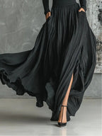 Close-up of a black pleated maxi skirt showing the pleat and slit detail