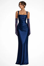 Woman wearing a navy blue satin square neck ruched maxi dress with sheer gloves