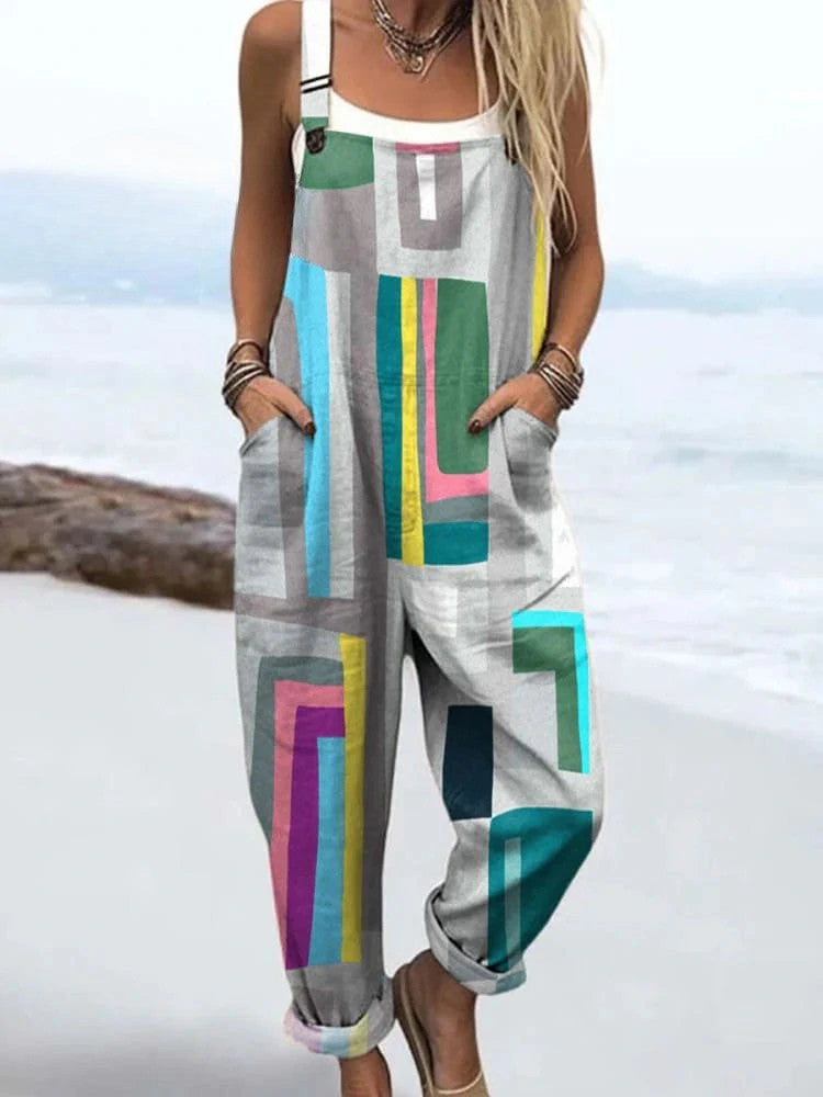 Woman wearing a grey multicolor geometric color-block wide-leg overall jumpsuit standing on a rocky beach