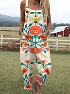 Woman wearing a cream sleeveless jumpsuit with a pink floral and bee print, front view on a farm