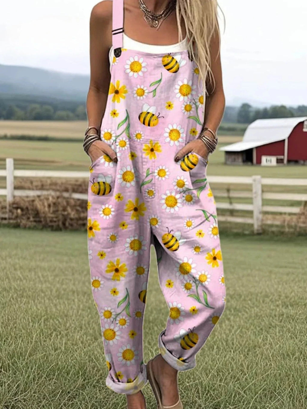 Woman wearing a pink-lavender overall jumpsuit with a yellow daisy and bee print on a farm