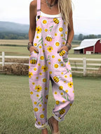 Woman wearing a pink-lavender overall jumpsuit with a yellow daisy and bee print on a farm