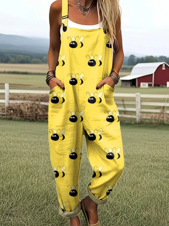 Woman wearing a yellow jumpsuit with a black bumblebee print standing in a farm field near a red barn