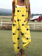 Woman wearing a yellow jumpsuit with a black bumblebee print standing in a farm field near a red barn