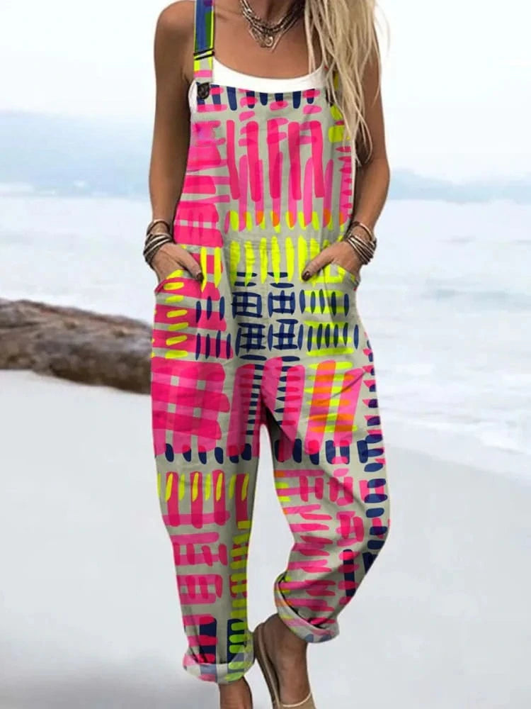 Woman wearing a pink, lime green and black abstract geometric print dungaree jumpsuit on a beach