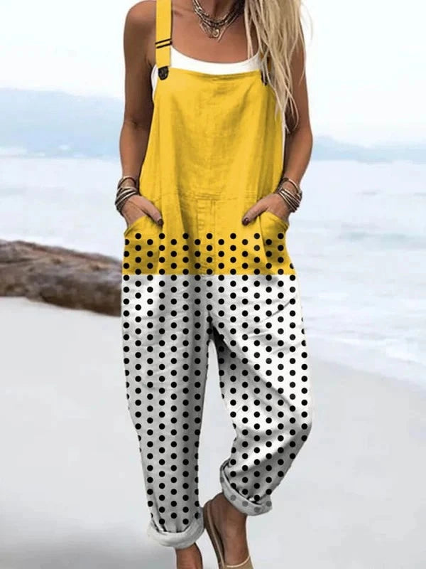 Woman wearing a yellow polka dot color-block sleeveless overall jumpsuit standing on a rocky beach