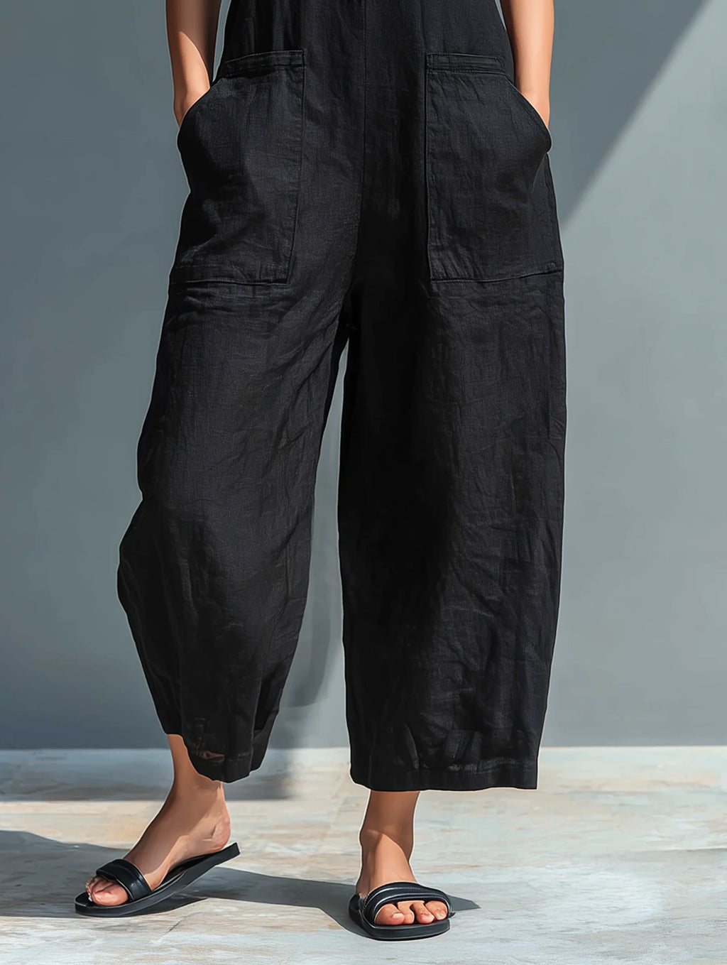 Close-up of a black minimalist sleeveless jumpsuit showing the neckline detail