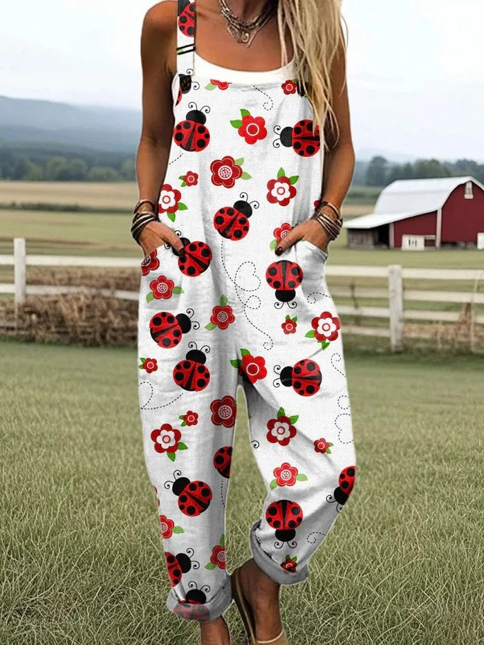 Woman wearing a white jumpsuit with a red ladybug and floral print standing in a farm field near a red barn