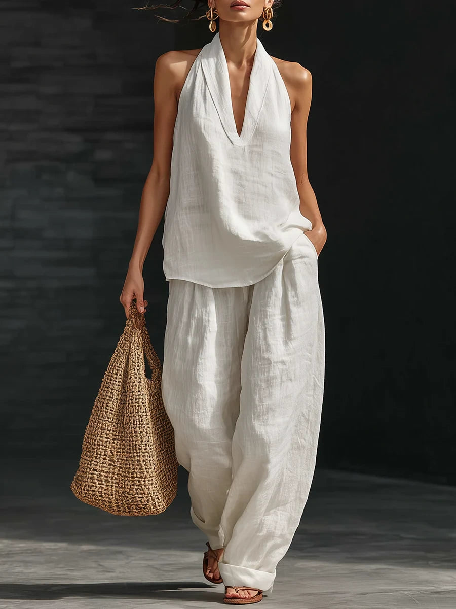 Woman wearing a white sleeveless wide-leg jumpsuit in a studio setting