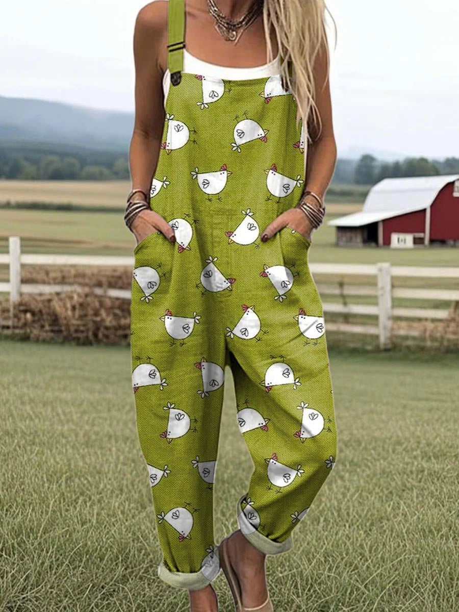 Woman wearing a green chick-print short-sleeve jumpsuit standing in a farm field near a red barn